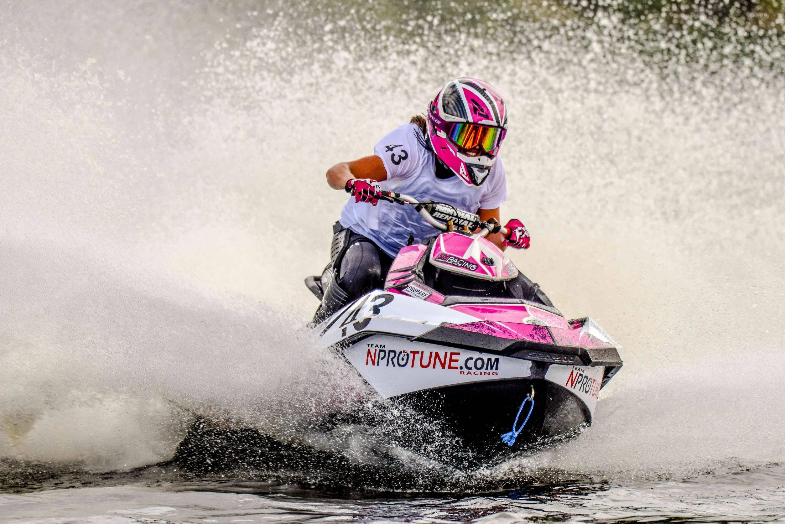 Rosa vattenskoter i full fart fart med en leende aquabikeförare på sadeln